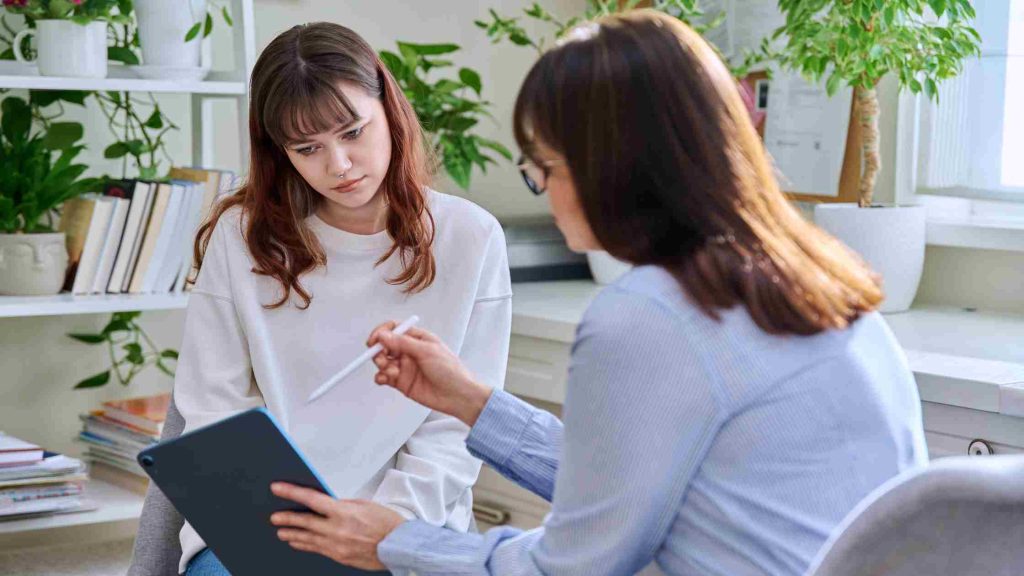 Therapist reviewing progress with a thoughtful teen, representing individual progress in outpatient treatment duration.
