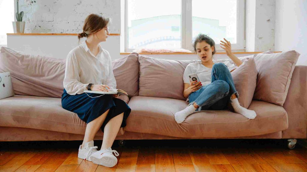 A therapist listens attentively to a teen sharing her thoughts, creating a safe and trusting space in trauma-focused therapy.