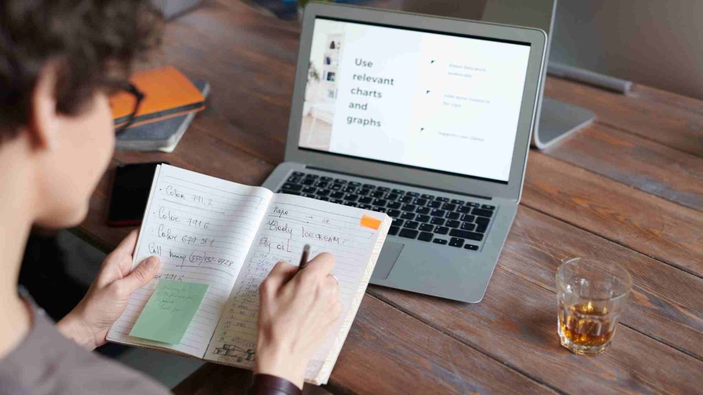 A teen takes notes while learning from a laptop, representing therapy helping teens build practical life skills.