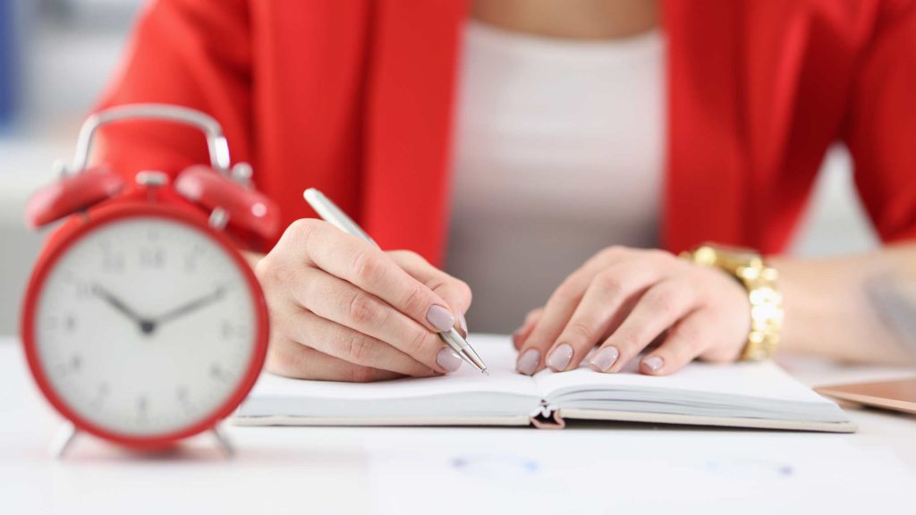 Close-up of a notebook with a clock nearby, symbolizing the time commitment difference between Teen PHP and IOP.