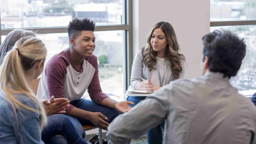 Teens sitting in a therapy group session, representing the supportive environment of a teen outpatient treatment program.